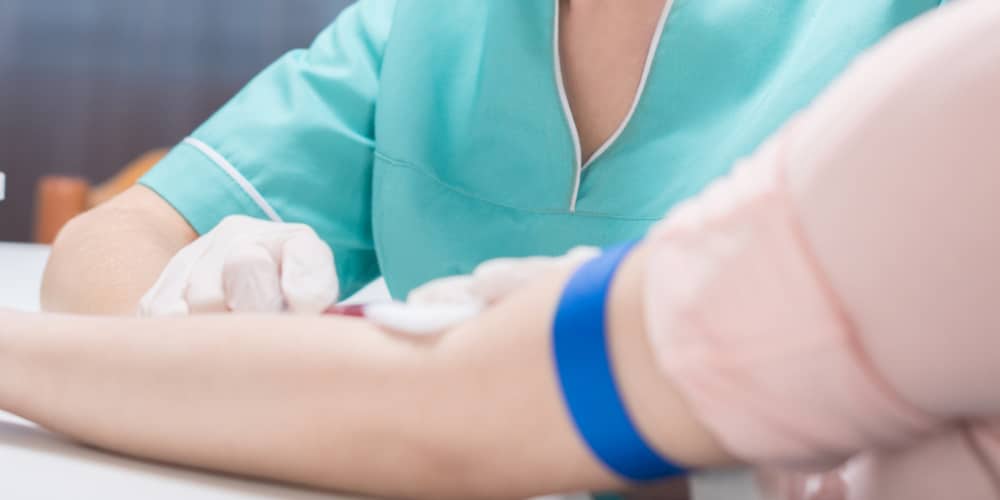 Hoe kan je reuma aantonen_ Een afbeelding van een arm waaruit bloed geprikt wordt door een verpleegkundige om te verbeelden hoe je reuma kunt aantonen