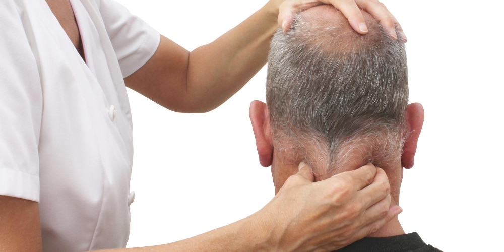 Wanneer moet je testen op fibromyalgie_ Een afbeelding van een man die een onderzoek krijgt van een vrouwelijke arts bij de spieren van zijn nek. Om uit te beelden wanneer je fibromyalgie moet testen